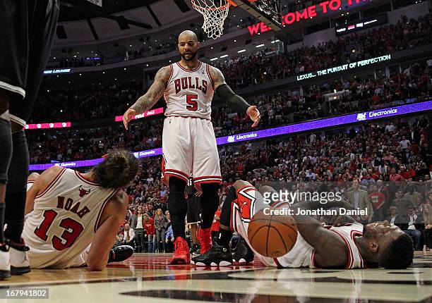 Carlos Boozer of the Chicago Bulls moves to help up teammates Joakim Noah and Nate Robinson after a play against the Brooklyn Nets in Game Six of the...