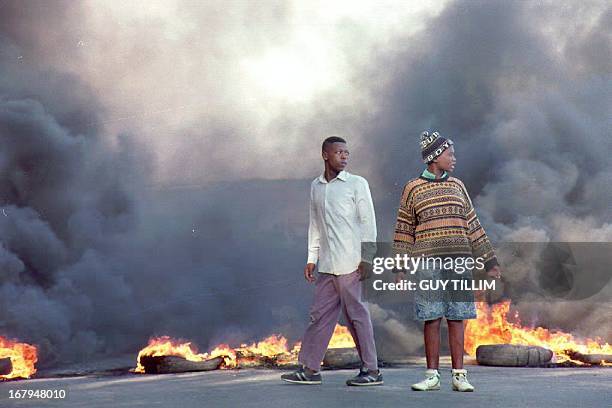 Township residents in Cape Town burn barricades 14 April 1993 as they prepare to march into the center of the city to protest the assassination of...