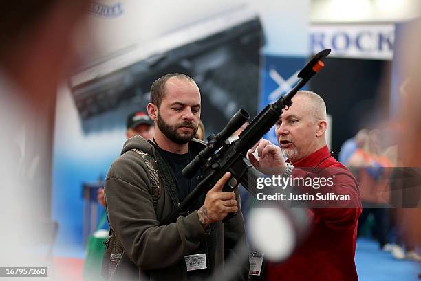 An attendee inspects a scope on an assault rifle during the 2013 NRA Annual Meeting and Exhibits at the George R. Brown Convention Center on May 3,...