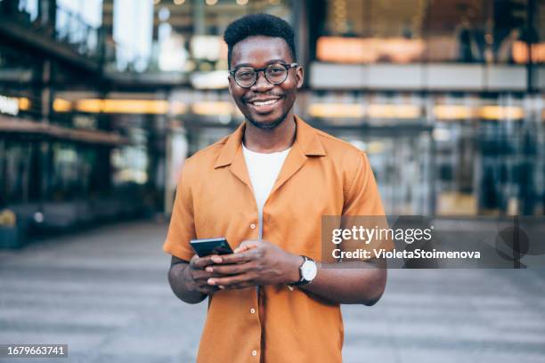 jovem sorridente usando smartphone na rua. - charmoso - fotografias e filmes do acervo
