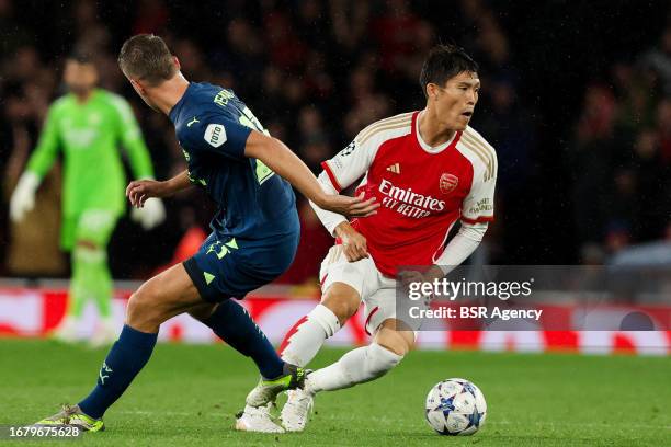 Takehiro Tomiyasu of Arsenal is challenged by Joey Veerman of PSV during the UEFA Champions League Group B match between Arsenal and PSV at Emirates...