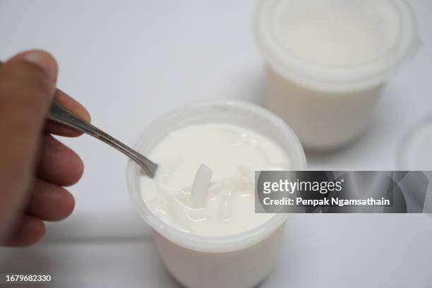 milk curd in plastic cup - spoon in hand stock pictures, royalty-free photos & images