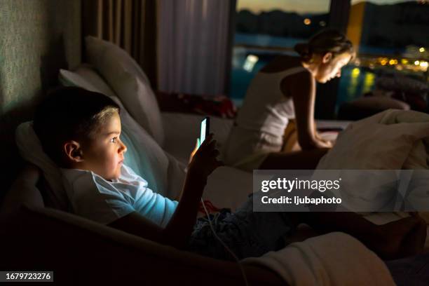 mother with boy using laptop and smartphone. - using phone and laptop stock pictures, royalty-free photos & images