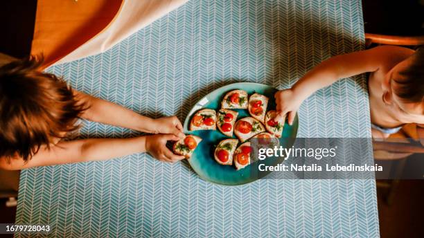 top view of kids' hands with vegetarian small sandwiches on a blue plate for breakfast - table aperitif stock-fotos und bilder