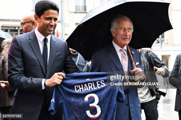 Paris Saint Germain's Qatari president Nasser al-Khelaifi offers Britain's King Charles III a Paris Saint Germain's jersey during a visit in...