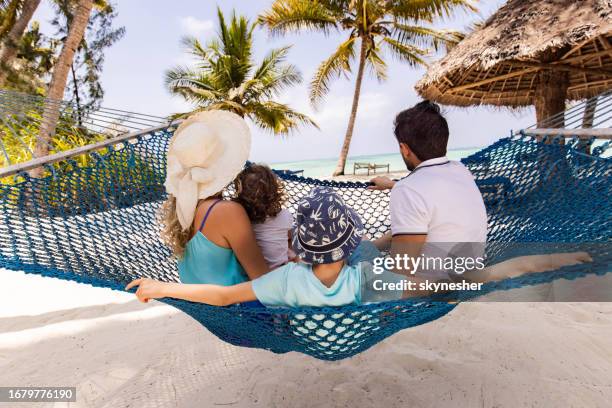 back view of a family relaxing in hammock on the beach. - family at beach stock pictures, royalty-free photos & images