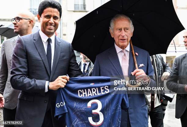 Paris Saint Germain's Qatari president Nasser al-Khelaifi offers Britain's King Charles III a Paris Saint Germain's jersey during a visit in...