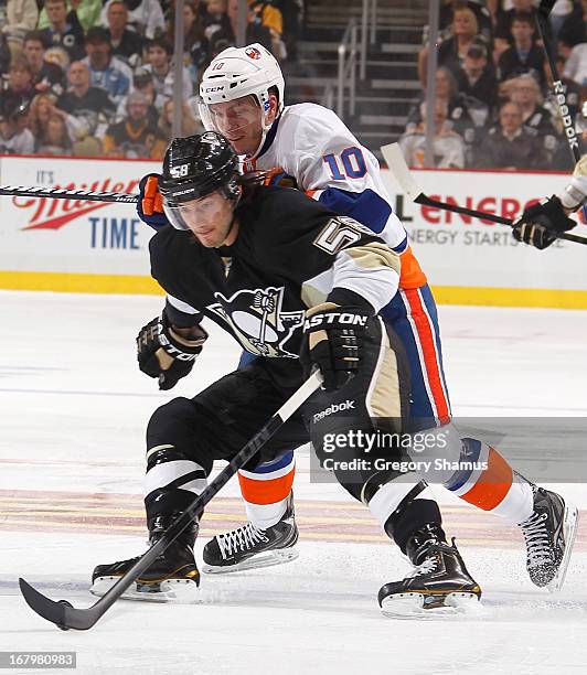 Kris Letang of the Pittsburgh Penguins moves the puck ahead of Keith Aucoin of the New York Islanders in Game Two of the Eastern Conference...