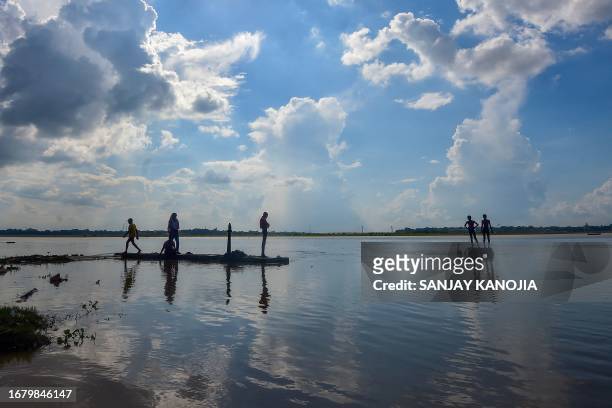 Boys walk on the banks of flooded river Ganges in Prayagraj on September 21, 2023. .