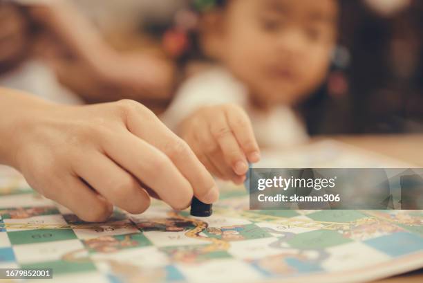 asian toddler enjoy playing snakes and ladders board games with mother at home - snakes and ladders stock pictures, royalty-free photos & images