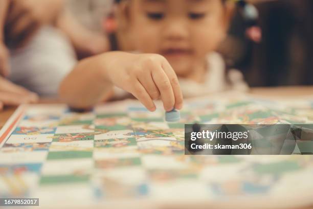 asian toddler enjoy playing snakes and ladders board games with mother at home - snakes and ladders stock pictures, royalty-free photos & images