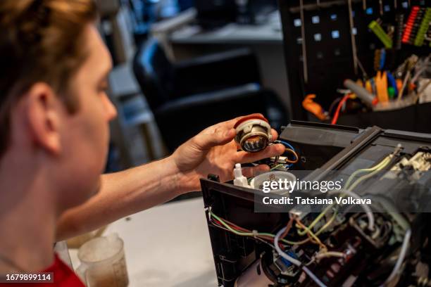 proficient repairman carefully disassembles coffee grinder installed inside coffee machine - pezzo di ricambio foto e immagini stock