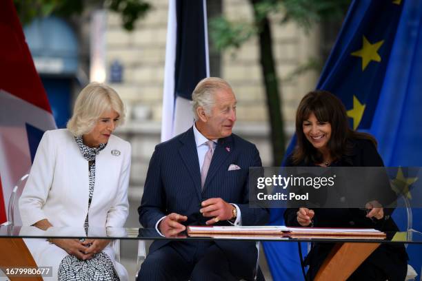 Queen Camilla, King Charles III and Paris' mayor Anne Hidalgo sign a book after visiting the central Paris Flower Market, named after her late...