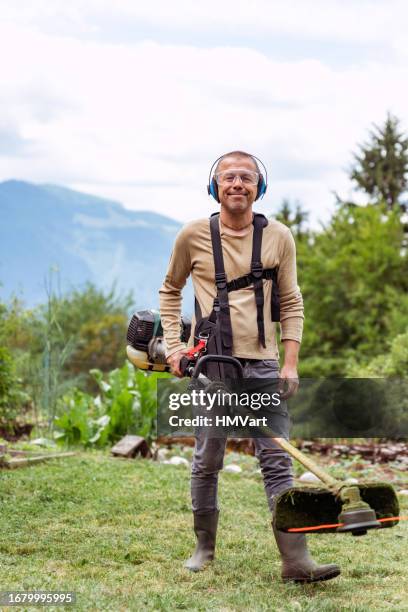 mature man on summer day moving the grass in the garden - cutting grass stock pictures, royalty-free photos & images