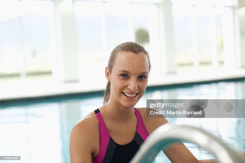 Smiling woman in bathing suit stepping out of swimming pool