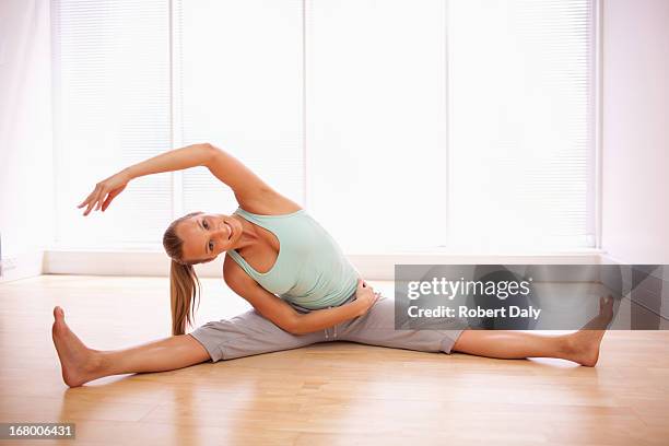 ritratto di donna sorridente mentre fa stretching con le gambe divaricate - gambe divaricate foto e immagini stock