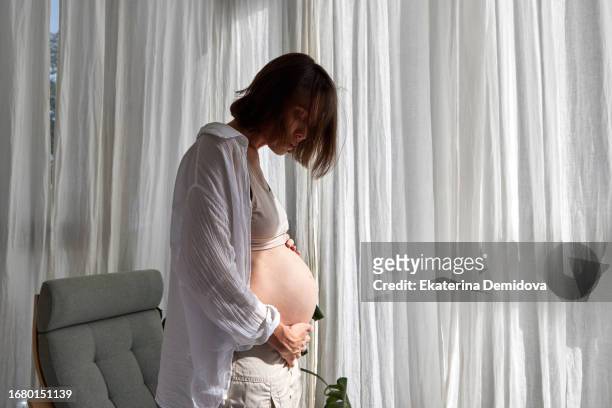 silhouette of pregnant woman standing against white background. side view of happy pregnant woman looking at belly. - weibliche brust schwanger stock-fotos und bilder