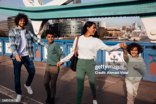 a family joyfully skip and jump together while holding hands. - skipping along stock pictures, royalty-free photos & images