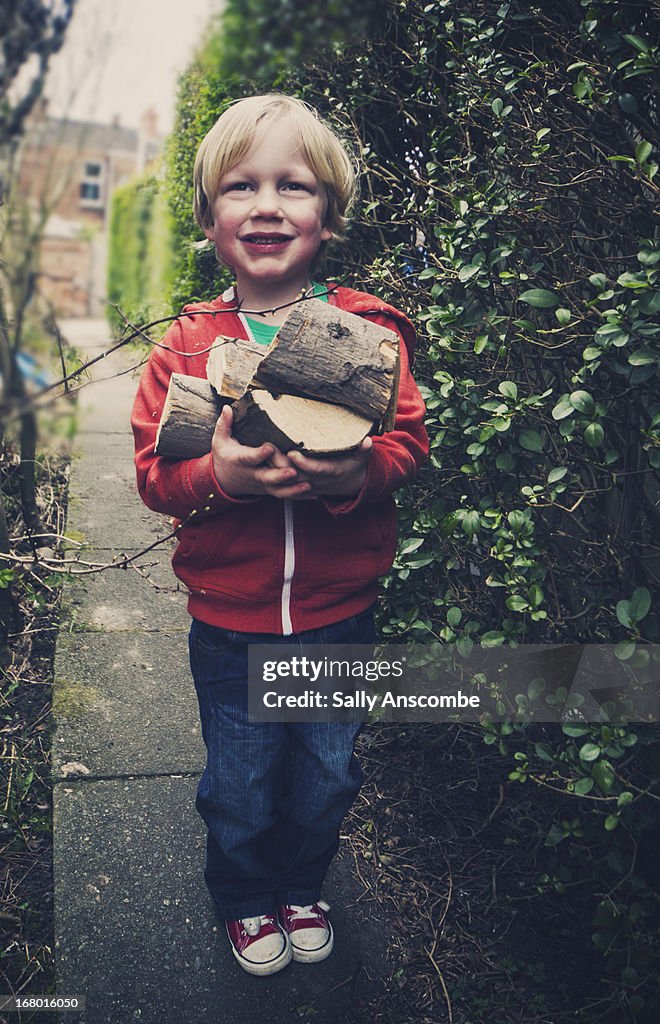 Child carrying logs for the fire