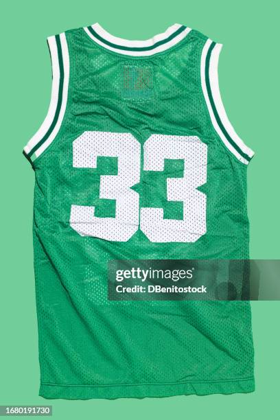 green basketball jersey with the number 33, on a green background. boston, basketball, sports equipment and legend concept. - uniforme de baloncesto fotografías e imágenes de stock