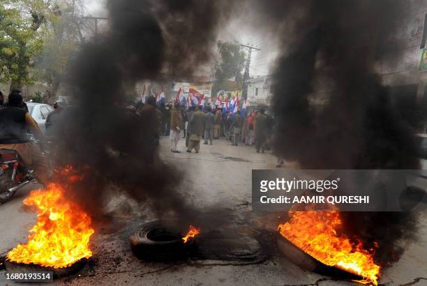 Pakistani Christians gather behind burning tyres during a protest against the killing of Christian government minister Shahbaz Bhatti in Islamabad by...
