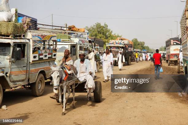 Sudanese move past trucks in Shendi, 190 kilometres from Khartoum, on September 21, 2023. The fighting in Sudan has killed at least 7,500 people,...