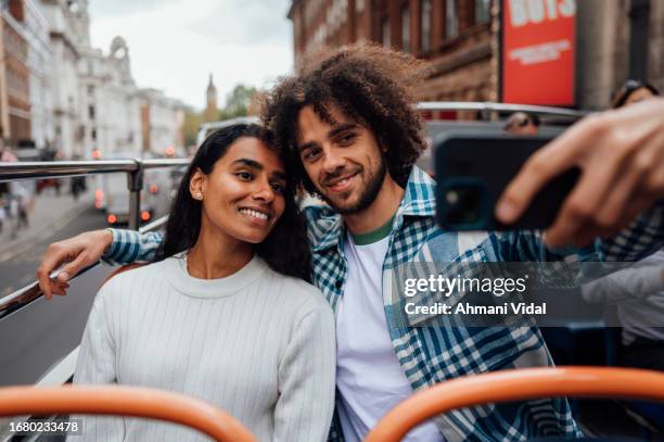 a couple ride an open top sightseeing bus around london - open top bus stock pictures, royalty-free photos & images