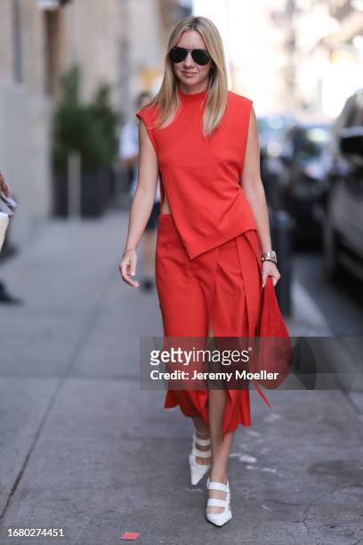 Lisa Aiken is seen outside Brandon Maxwell show wearing black aviator sunnies, red asymmetric top, matching red skirt with open front, red handbag...