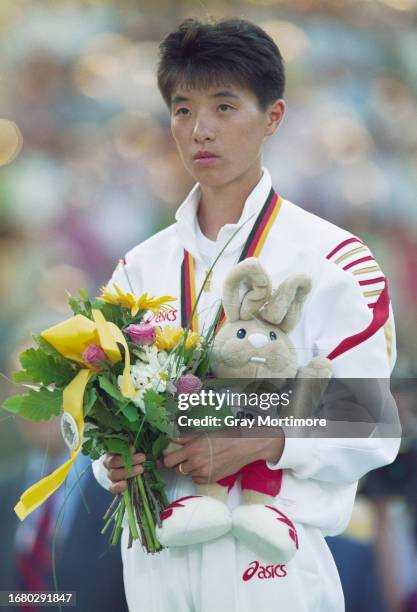 Junko Asari from Japan stands on the podium with her gold medal, rabbit mascot and a bouquet of flowers after winning the Women's Marathon race at...