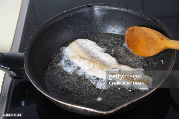 someone fries a fish in oil in the kitchen. - fried seafood stock pictures, royalty-free photos & images