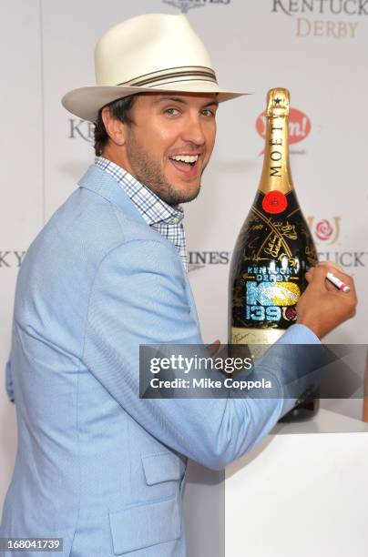 Singer Luke Bryan signs the Moet & Chandon 6L for the Churchill Downs Foundation during the 139th Kentucky Derby at Churchill Downs on May 4, 2013 in...