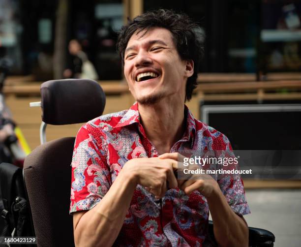 young man with cerebral palsy laughing outdoors in city. - developmental disability stock pictures, royalty-free photos & images