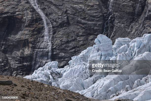 Fissures cover the ice tongue of the Pasterze glacier descending next to rock and a waterfall the glacier once covered on September 12, 2023 near...