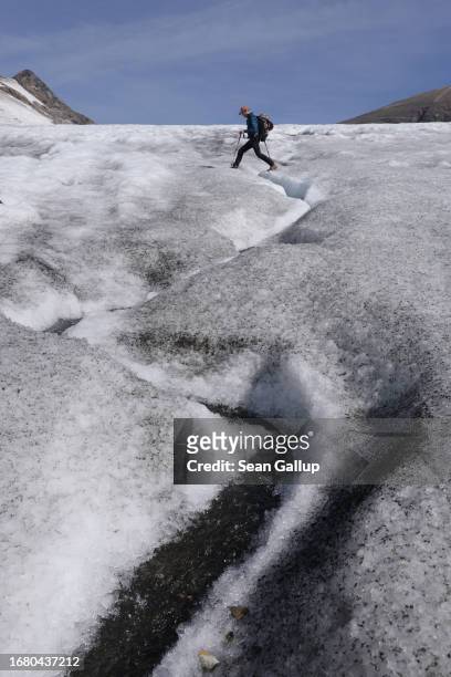 Scientist with a team from the University of Graz walks across a rivulet of meltwater on the plateau of the Pasterze glacier on September 12, 2023...