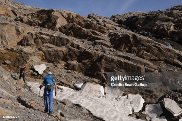 Scientists from the University of Graz walk past melting snow as they ascend to the plateau of the Pasterze glacier on September 12, 2023 near...