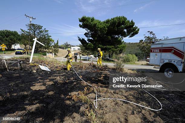 Two firefighters from Cameron Park Fire in Sacramento douse hot spots across the street from homes which escaped damage from the Springs wildfire in...