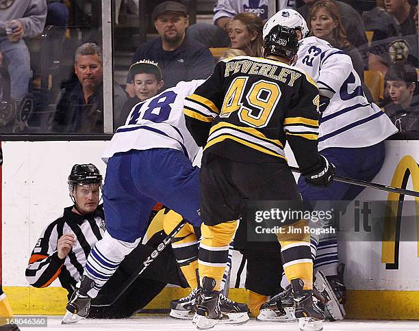 An official falls to the ice as Ryan Hamilton and Ryan O'Byrne of the Toronto Maple Leafs and Rich Peverley of the Boston Bruins fight for the puck...