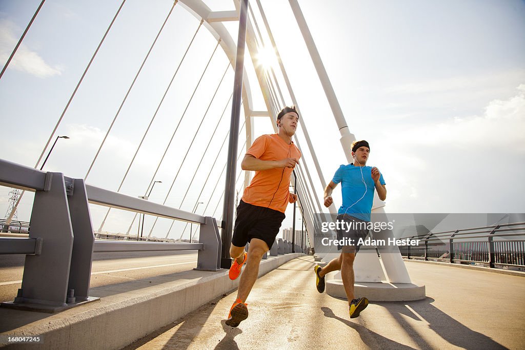 Two young males jogging in a urban area together.