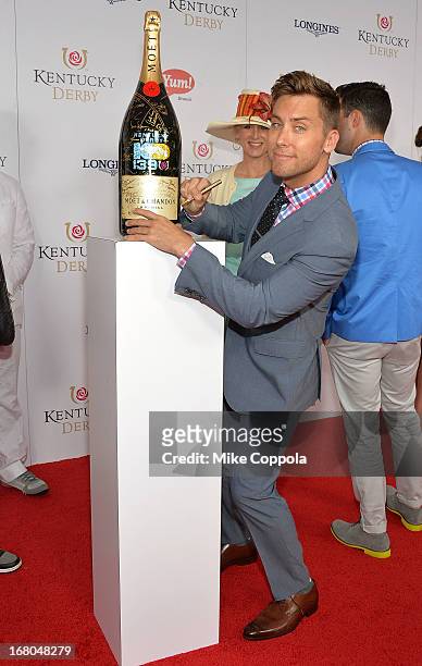 Singer Lance Bass signs the Moet & Chandon 6L for the Churchill Downs Foundation during the 139th Kentucky Derby at Churchill Downs on May 4, 2013 in...