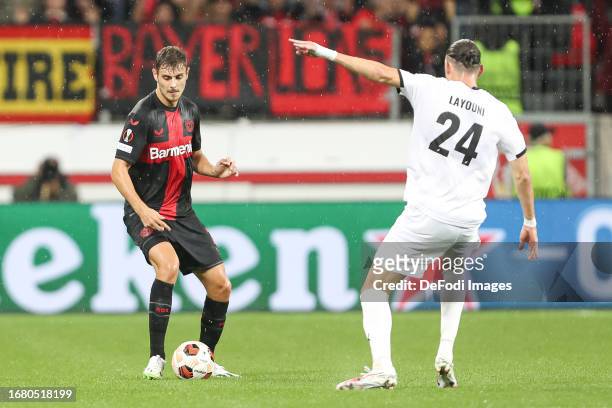Josip Stanisic of Bayer 04 Leverkusen and Amor Layouni of BK Haecken battle for the ball during the UEFA Europa League 2023/24 group stage match...