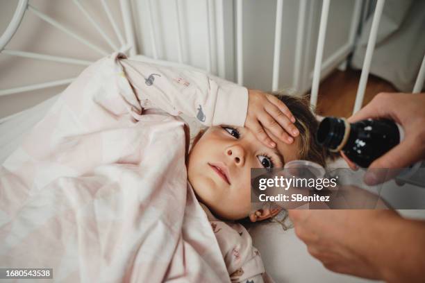 mother giving daughter cough syrup - hand over mouth stock pictures, royalty-free photos & images