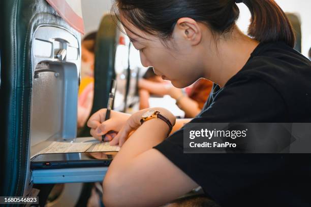 entering the country by plan, a woman is filling out the immigration information card - data entry form stock pictures, royalty-free photos & images