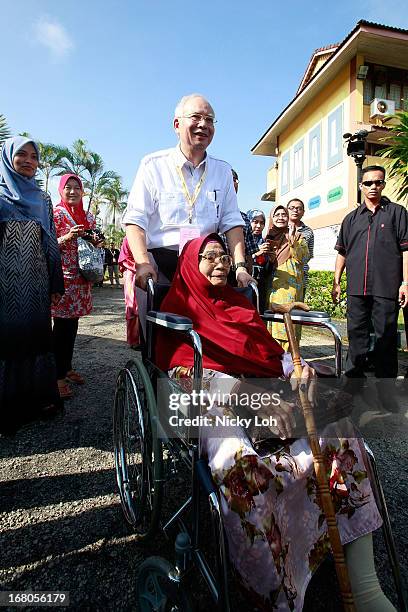 Malaysia's Prime Minister and Barisan Nasional chairman Najib Razak pushes a voter in a wheelchair to a polling station for the media during election...