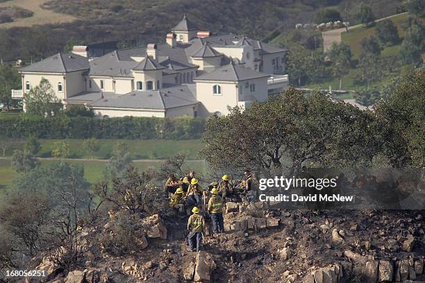 An expansive luxury home sits in the distance as firefighters take a break while constructing firelines by hand at the Springs fire on May 4, 2013...