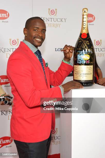 Keith Robinson signs the Moet & Chandon 6L for the Churchill Downs Foundation during the 139th Kentucky Derby at Churchill Downs on May 4, 2013 in...