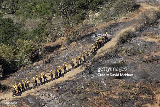 Column of elite U.S. Forest Service Hotshot firefighters walk along the edge of the black near Hidden Valley at the Springs fire on May 4, 2013 near...