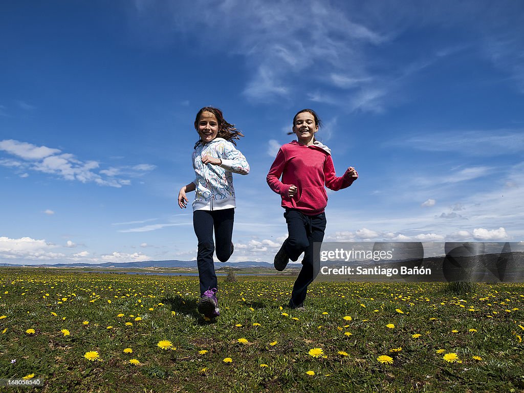 Girls running happy in flowered grass