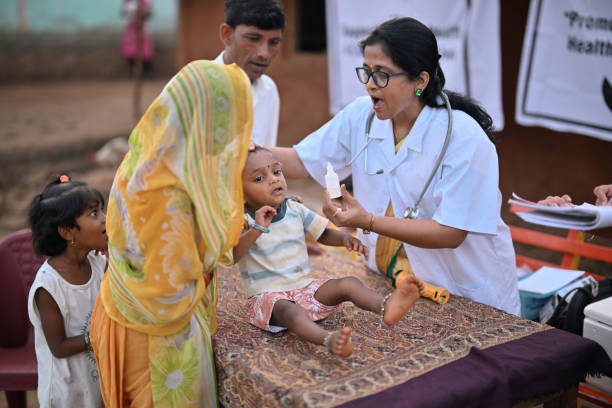 uma médica administra dose de poliomielite a uma criança durante um acampamento de saúde rural - fotos de criança com poliomielite, fotos e imagens livres de direitos autorais