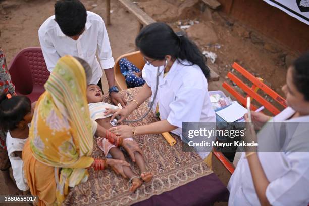 doctor examines a baby during a rural health care camp - primary care stock pictures, royalty-free photos & images
