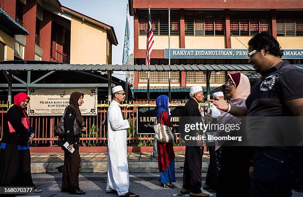 Voters wait in line outside a polling station for the general election in the Kampung Baru area of Kuala Lumpur, Malaysia, on Sunday, May 5, 2013....